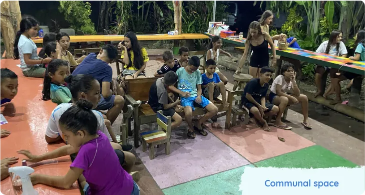 Children and adults gathered in a colourful communal outdoor space. Text reads Communal space. 
